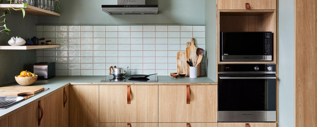 Kitchen scene with green walls, white tiles and wood panel cupboard fronts